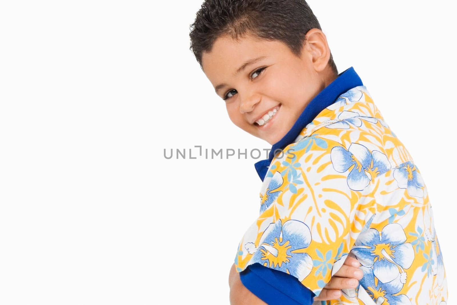 Side profile of a boy standing with his arms crossed and smiling