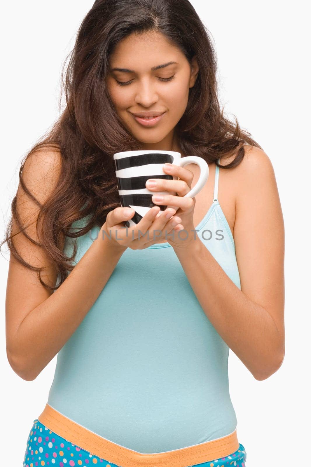 Close-up of a young woman holding a mug of coffee and smiling