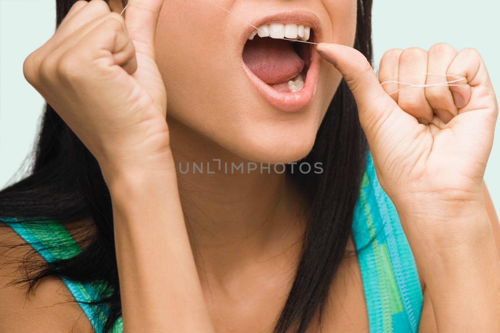 Close-up of a young woman flossing her teeth