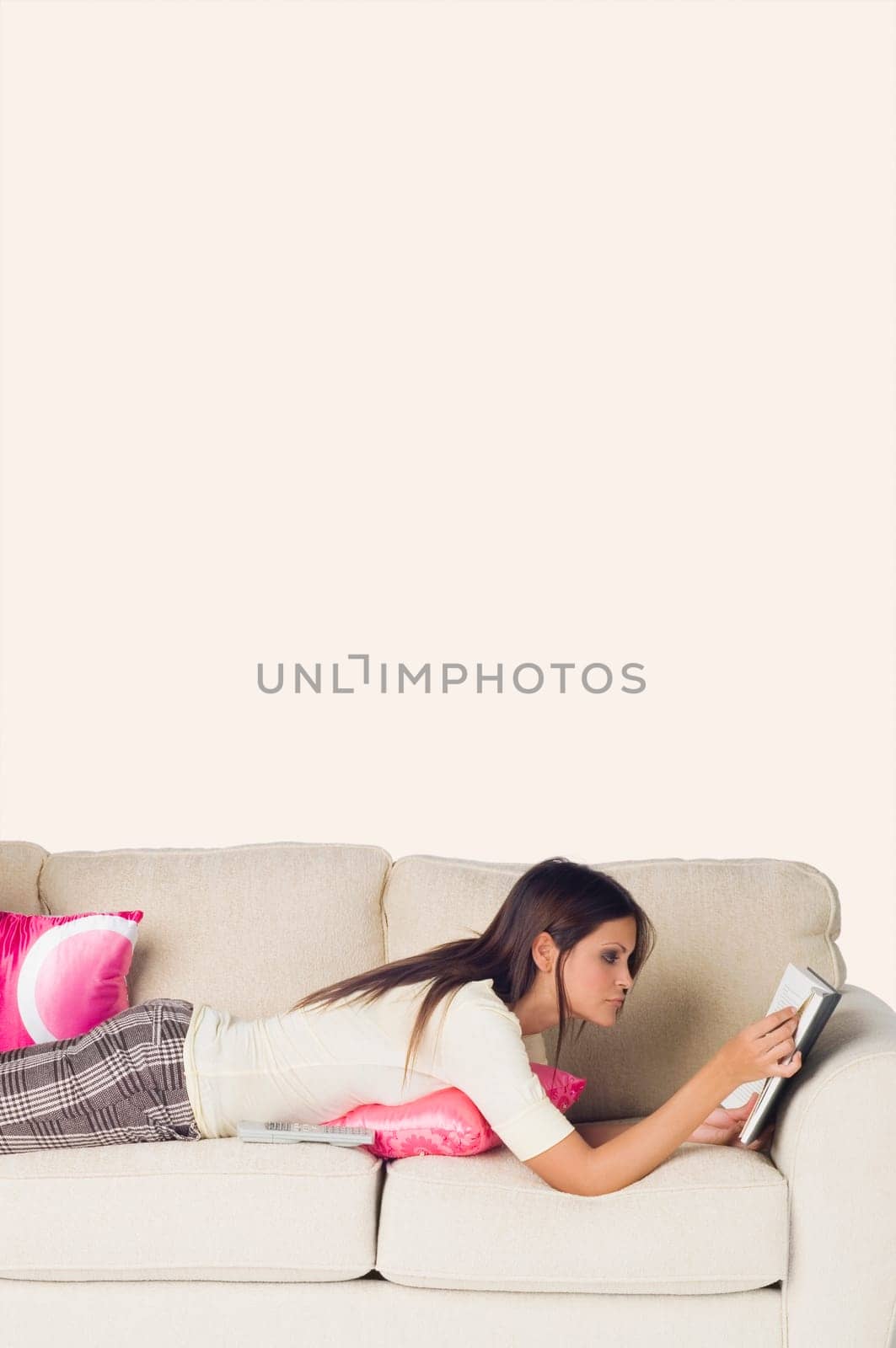 Side profile of a young woman lying on a couch and reading a book