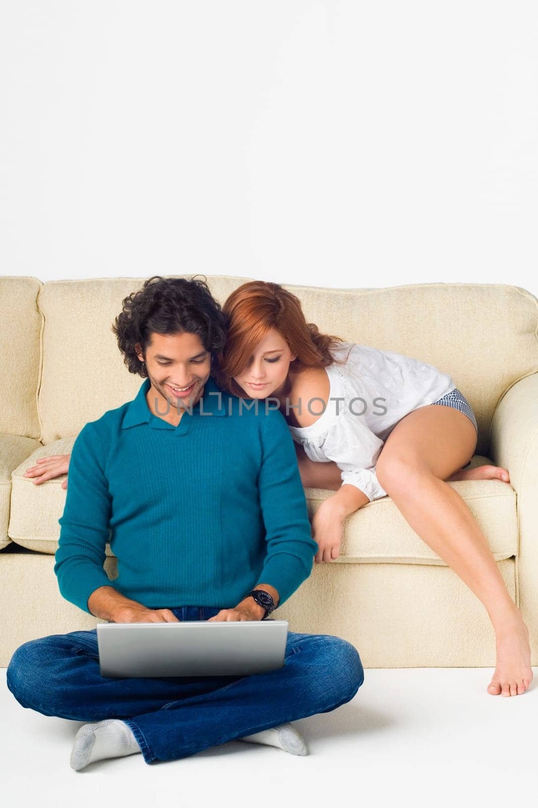 Young man using a laptop with a young woman leaning over him