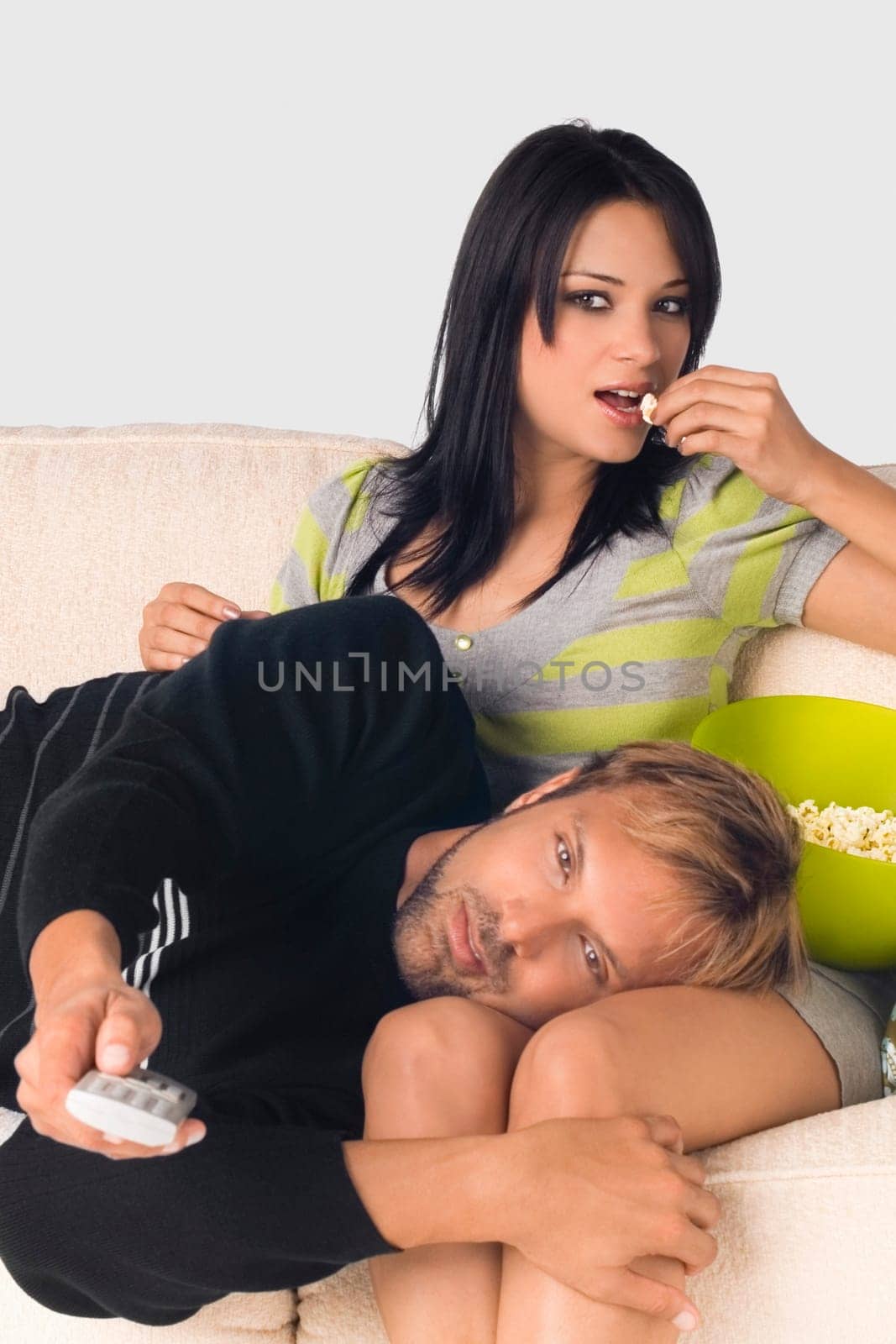 Mid adult man lying on the lap of a young woman and holding a remote control