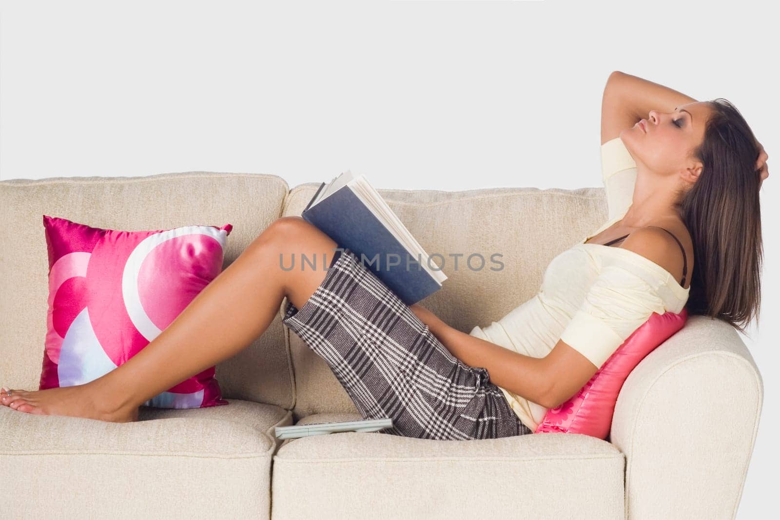 Side profile of a young woman reclining on a couch and holding a book