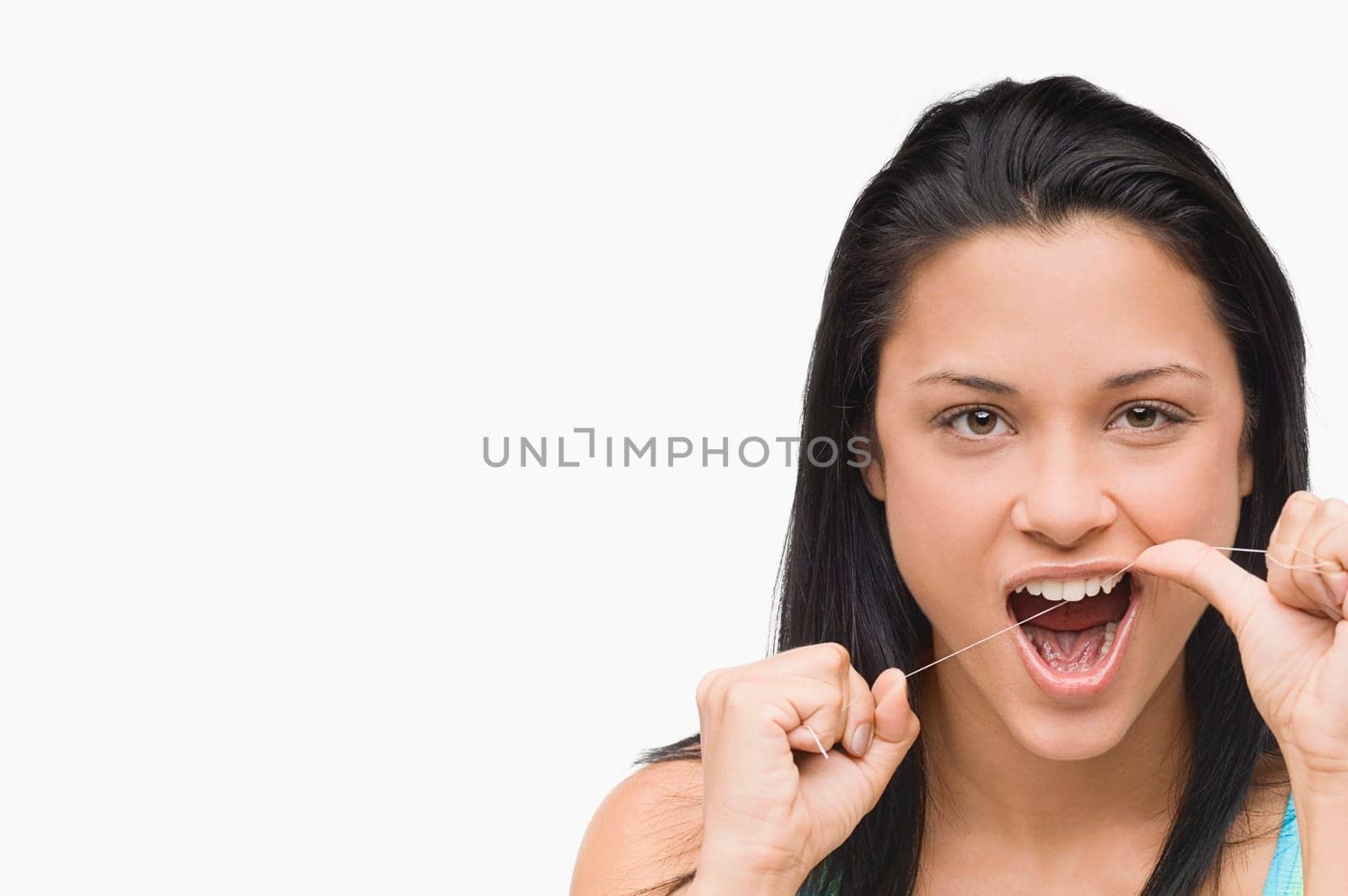 Portrait of a young woman flossing her teeth