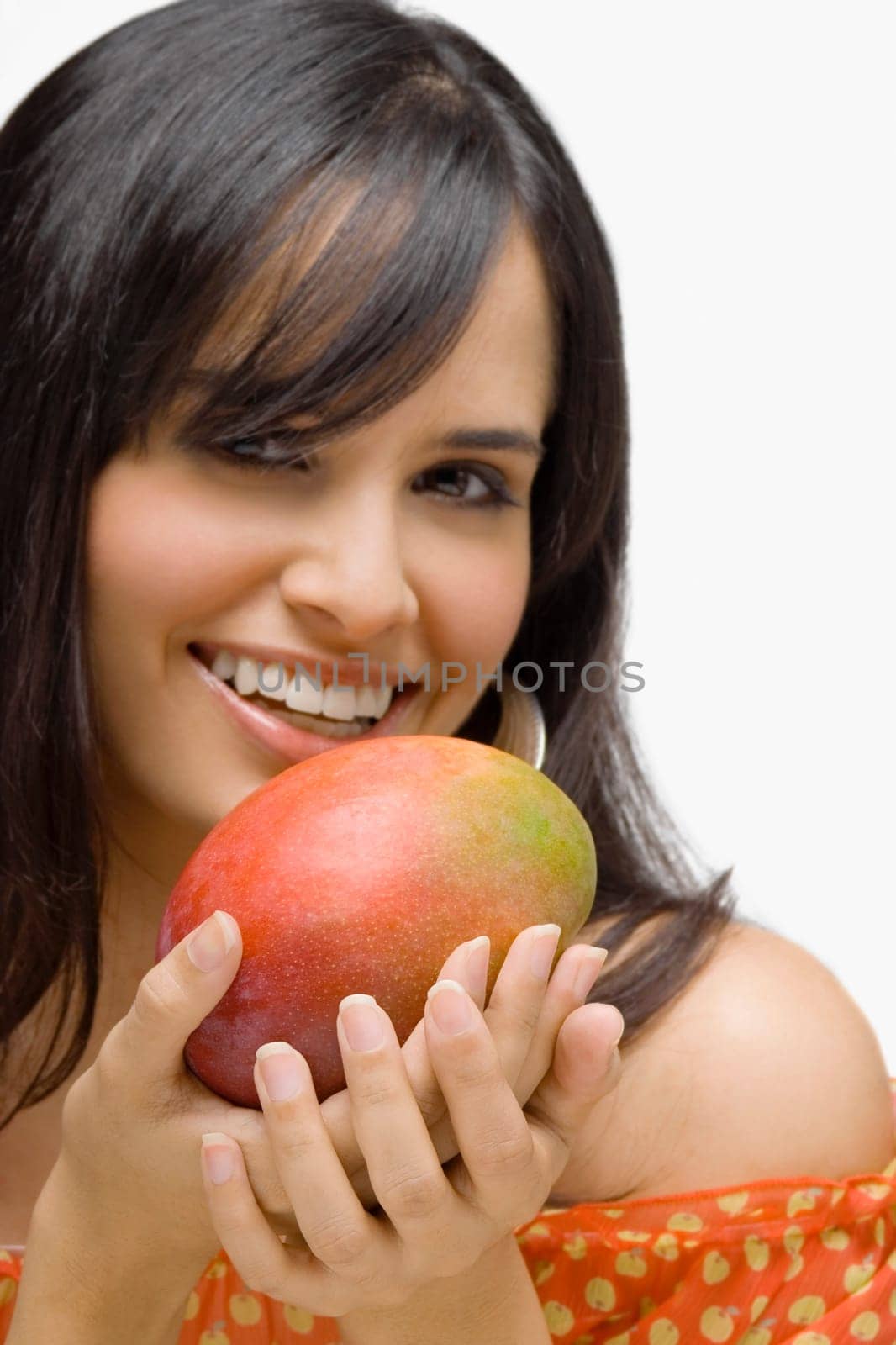 Portrait of a young woman holding a mango and smiling