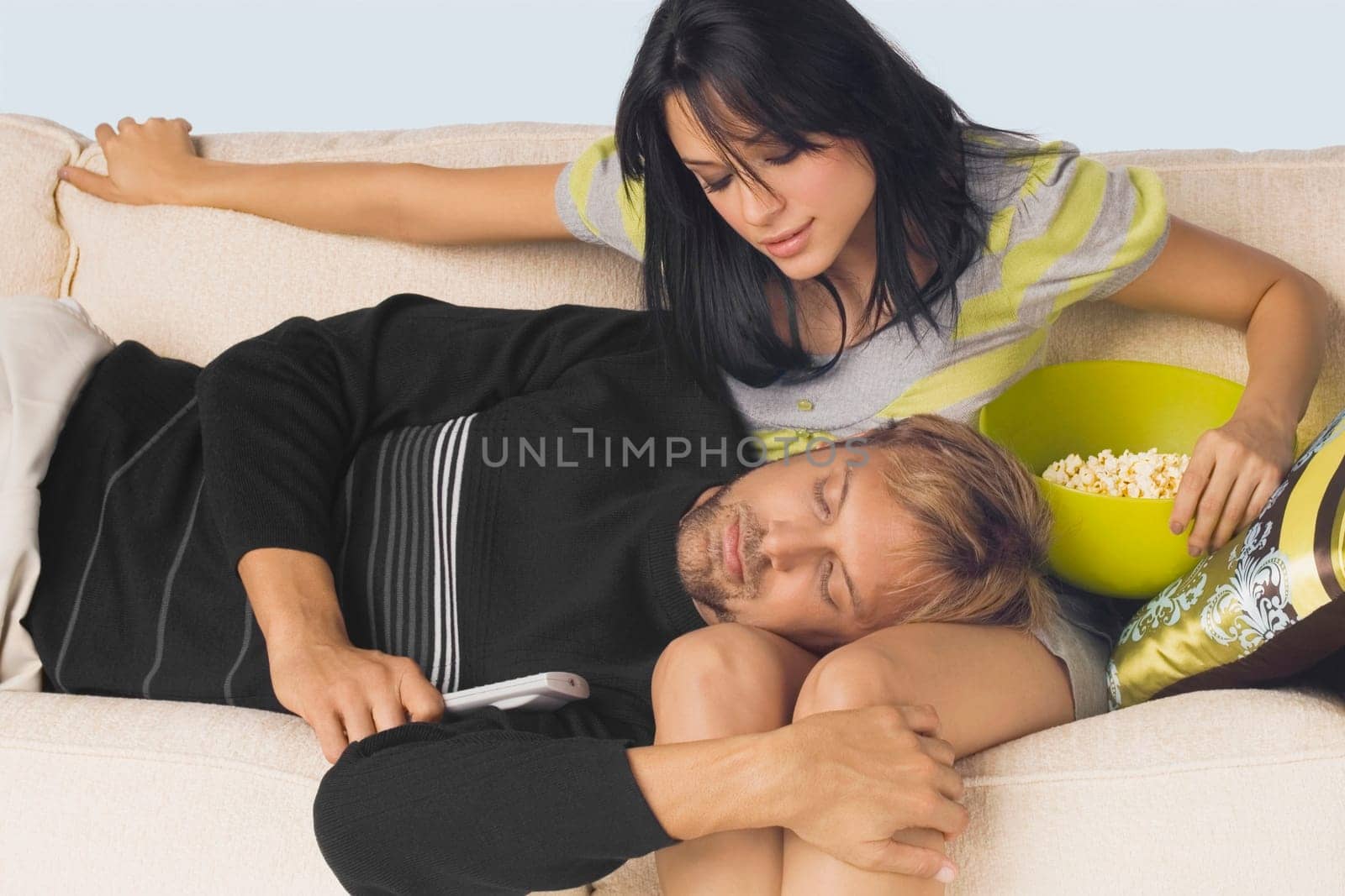 Mid adult man sleeping on the lap of a young woman sitting on a couch