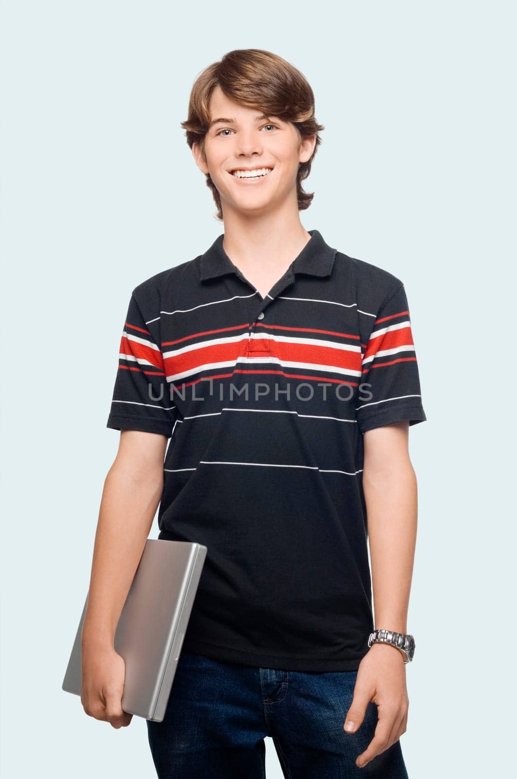 Portrait of a teenage boy holding a laptop and smiling