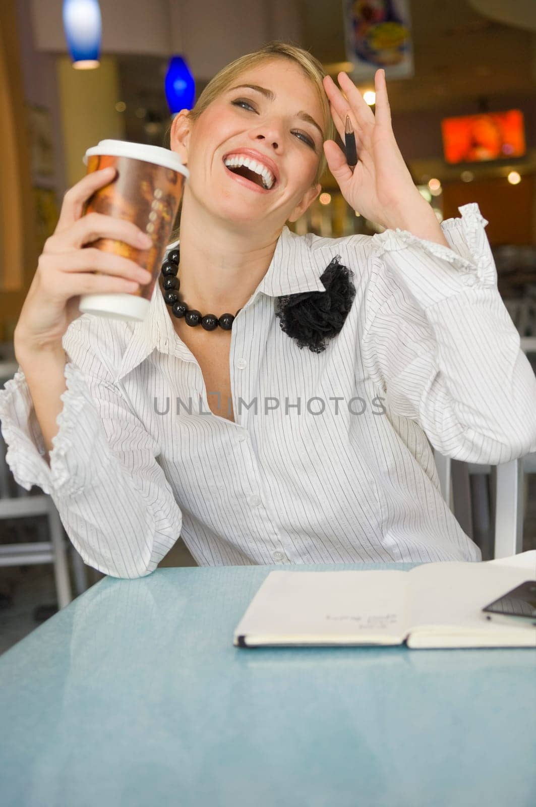 Businesswoman holding a disposable cup and smiling in a restaurant