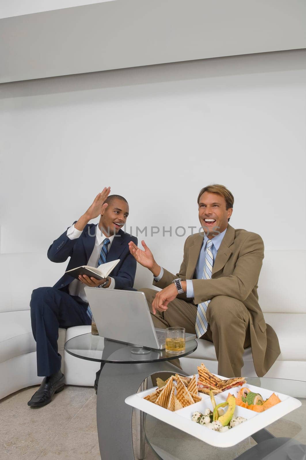 Two businessmen sitting in front of a laptop and smiling
