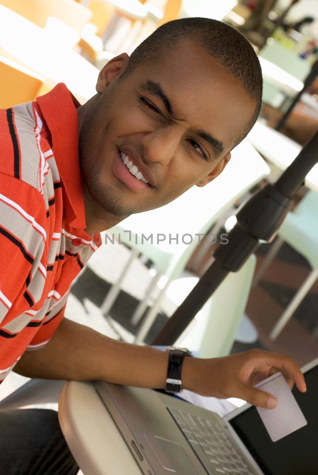Close-up of a young man winking and holding a credit card