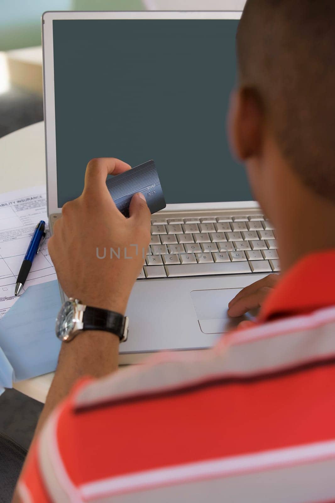 Young man using a laptop and holding a credit card