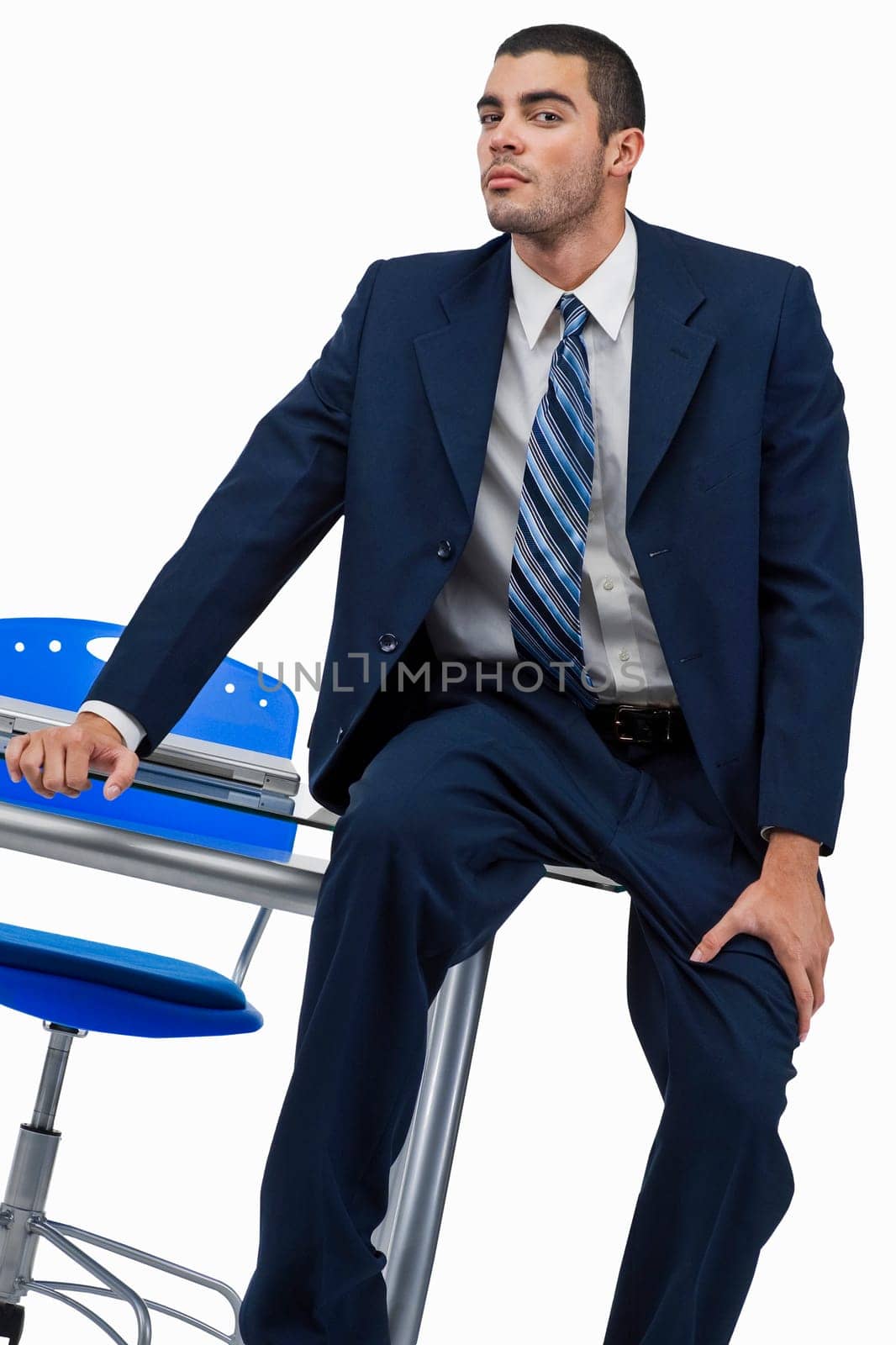 Portrait of a businessman sitting on a desk in an office