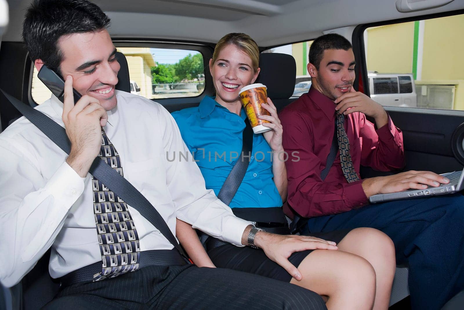 Close-up of a businesswoman sitting between two businessmen in a car and smiling