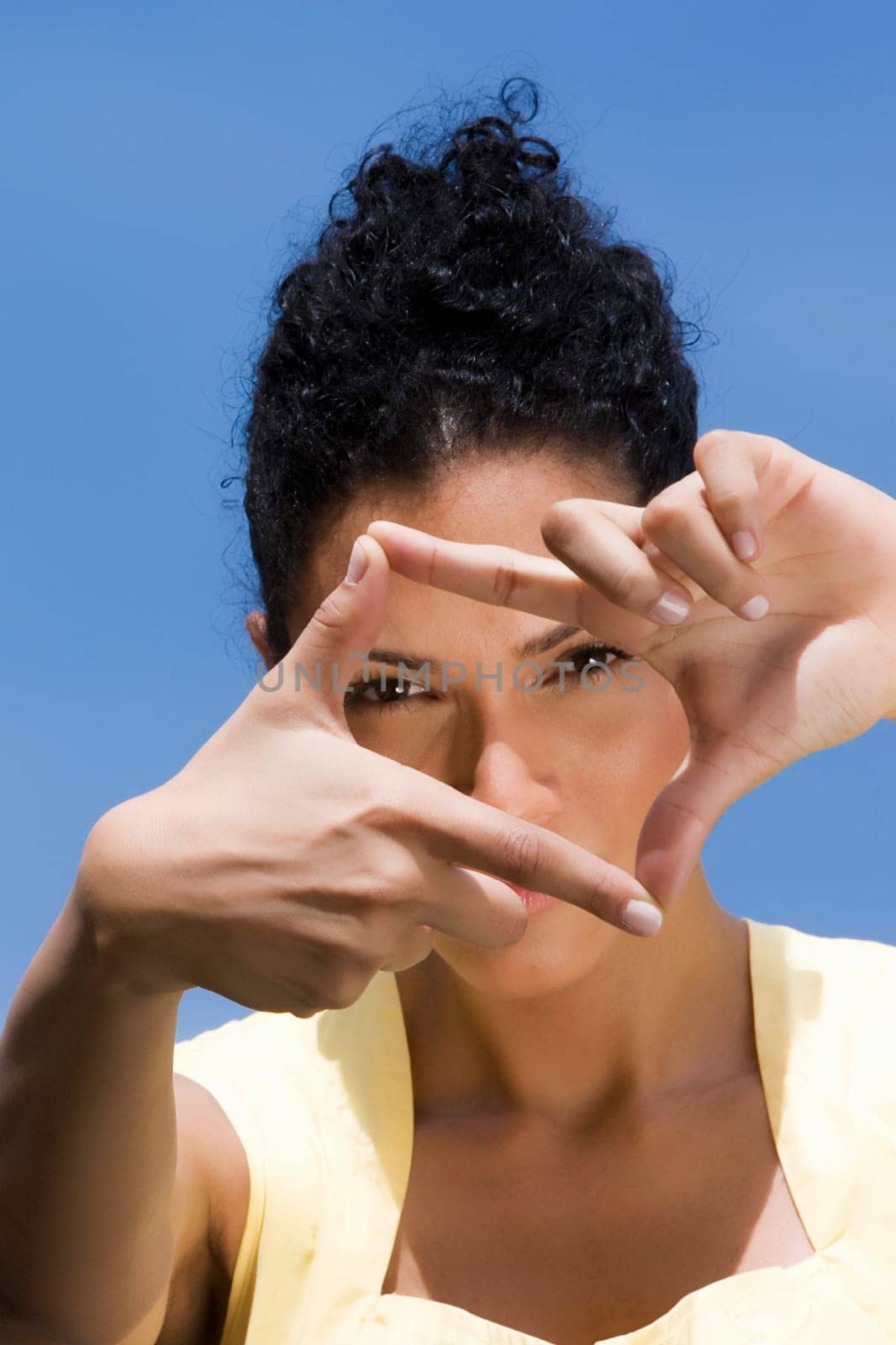 Portrait of a young woman making a finger frame in front of her face
