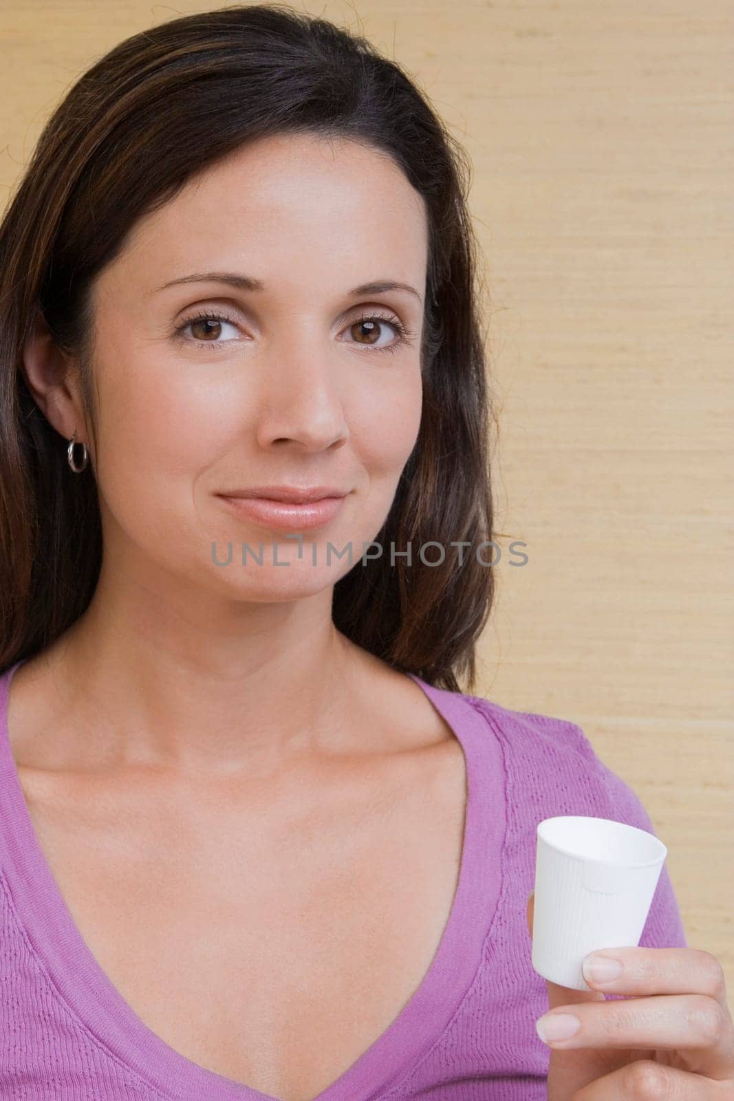 Portrait of a mid adult woman holding a cup of mouthwash