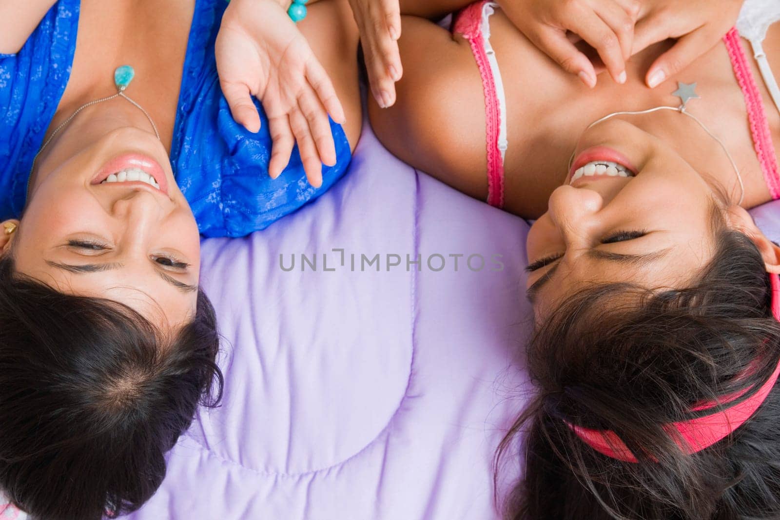 High angle view of a young woman and a teenage girl lying on the bed and smiling
