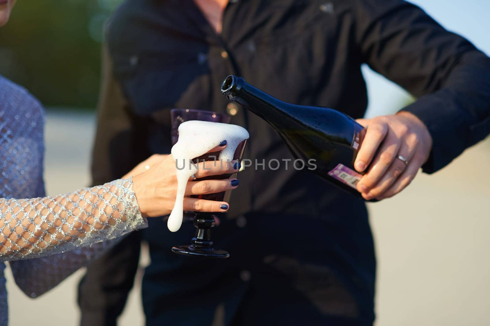 Holding a glass, pour champagne and it foams. Champagne foam.