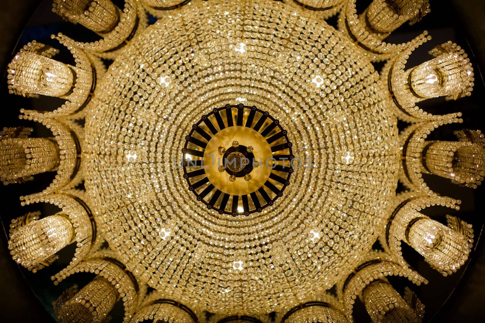 A view from the bottom up to a symmetrical beautiful chandelier. A big beautiful lust on a lot of light bulbs.