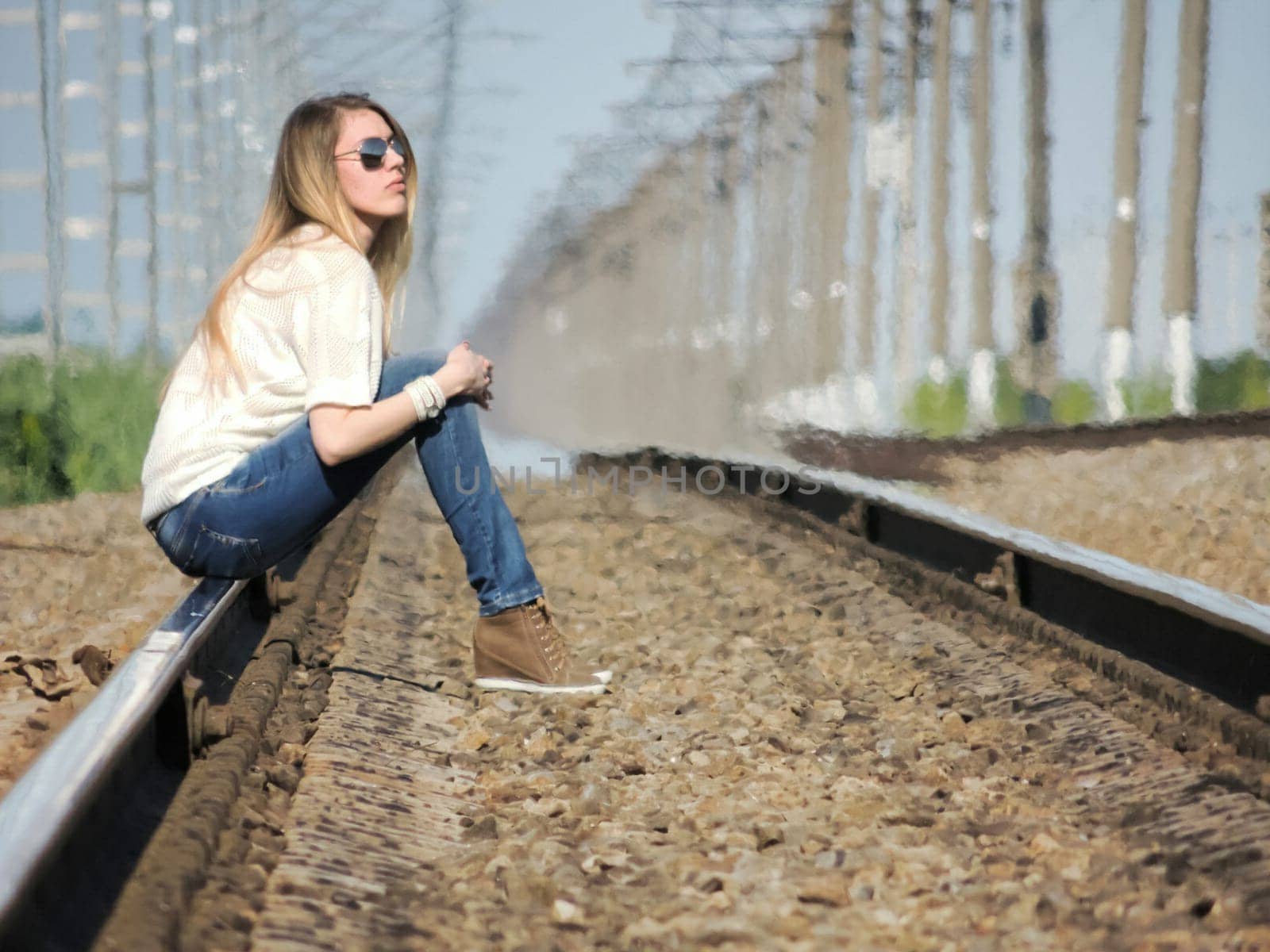 A blonde girl sits on the tracks. Walk to the waiting station.