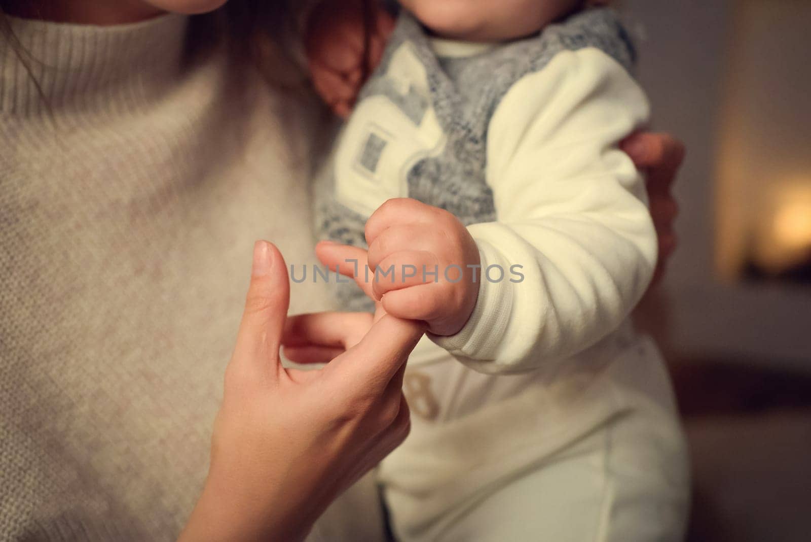 The child grabbed his mother's finger. The mother is holding the child in her arms.