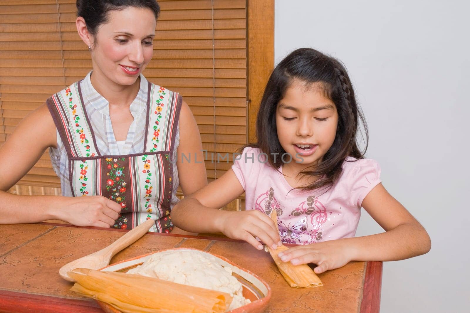 Girl preparing bread with her mother in the kitchen