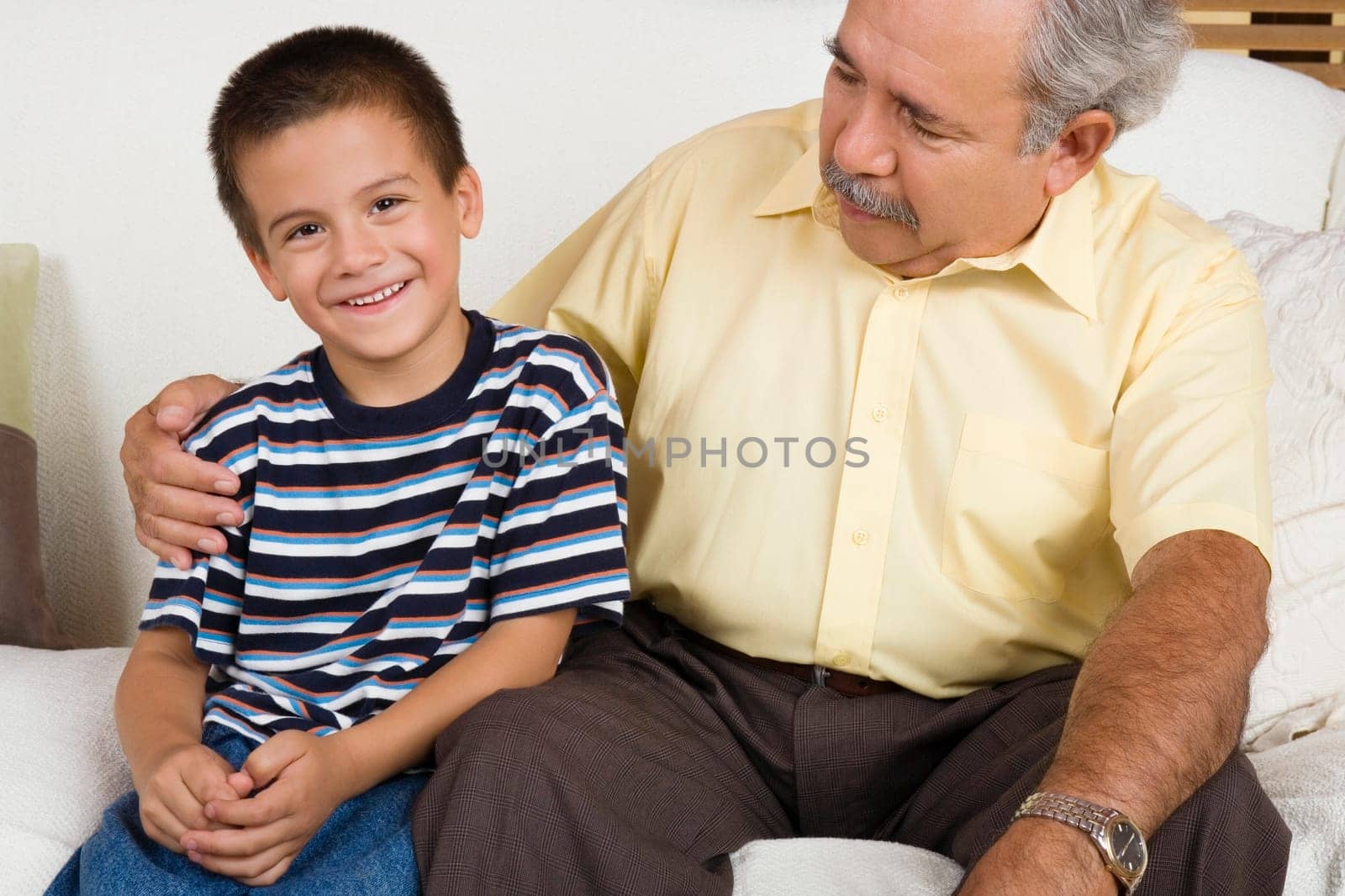 Portrait of a boy sitting with his grandfather on a couch and smiling