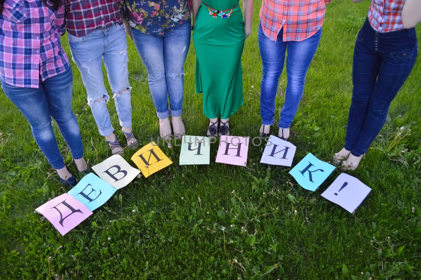 Women stand on the lawn in a semicircle. There are pieces of paper on the grass.