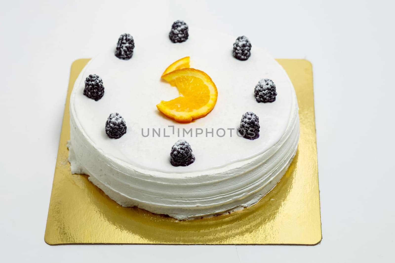 a White cake decorated with blackberries and orange.
