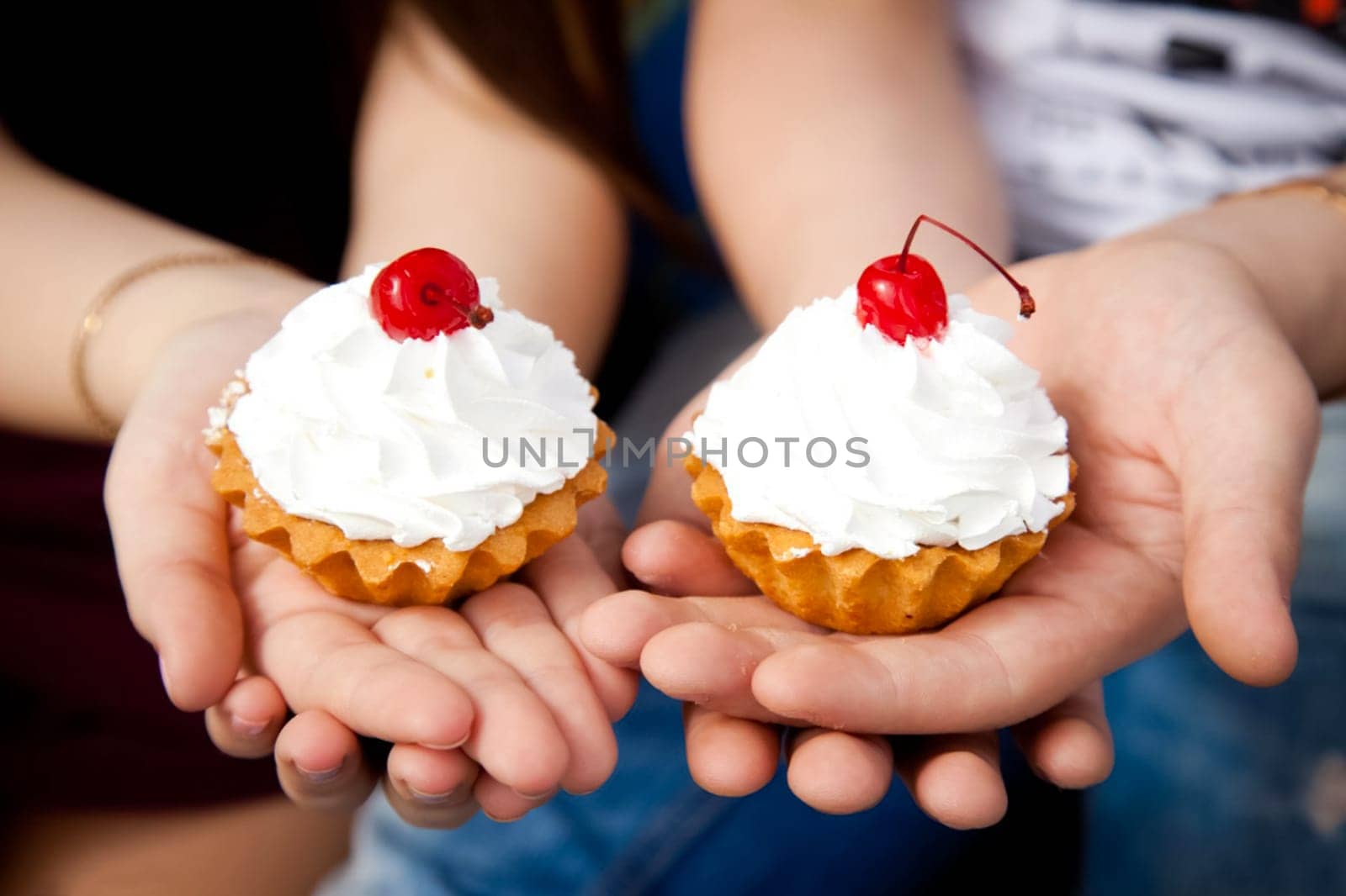 cupcakes with cream. Two cherry cakes on top. Cake in hand