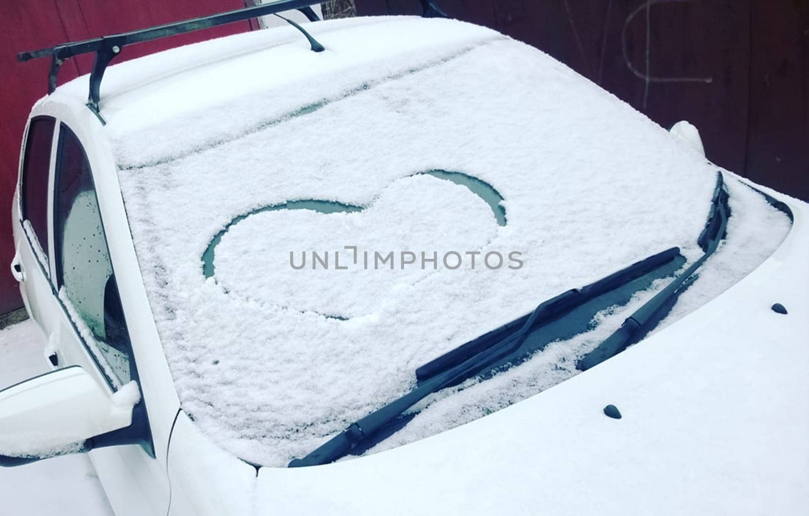 Painted heart in the snow by car in winter.