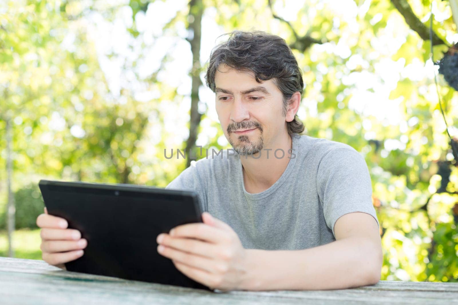 Young man relaxing with a tablet computer at a garden