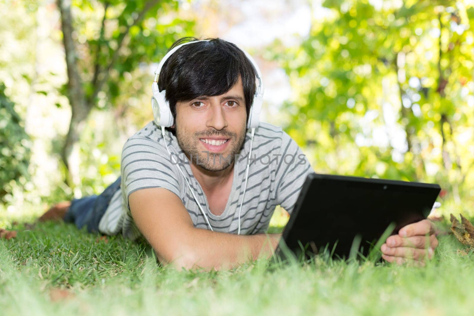 Young man relaxing with a tablet computer at a garden