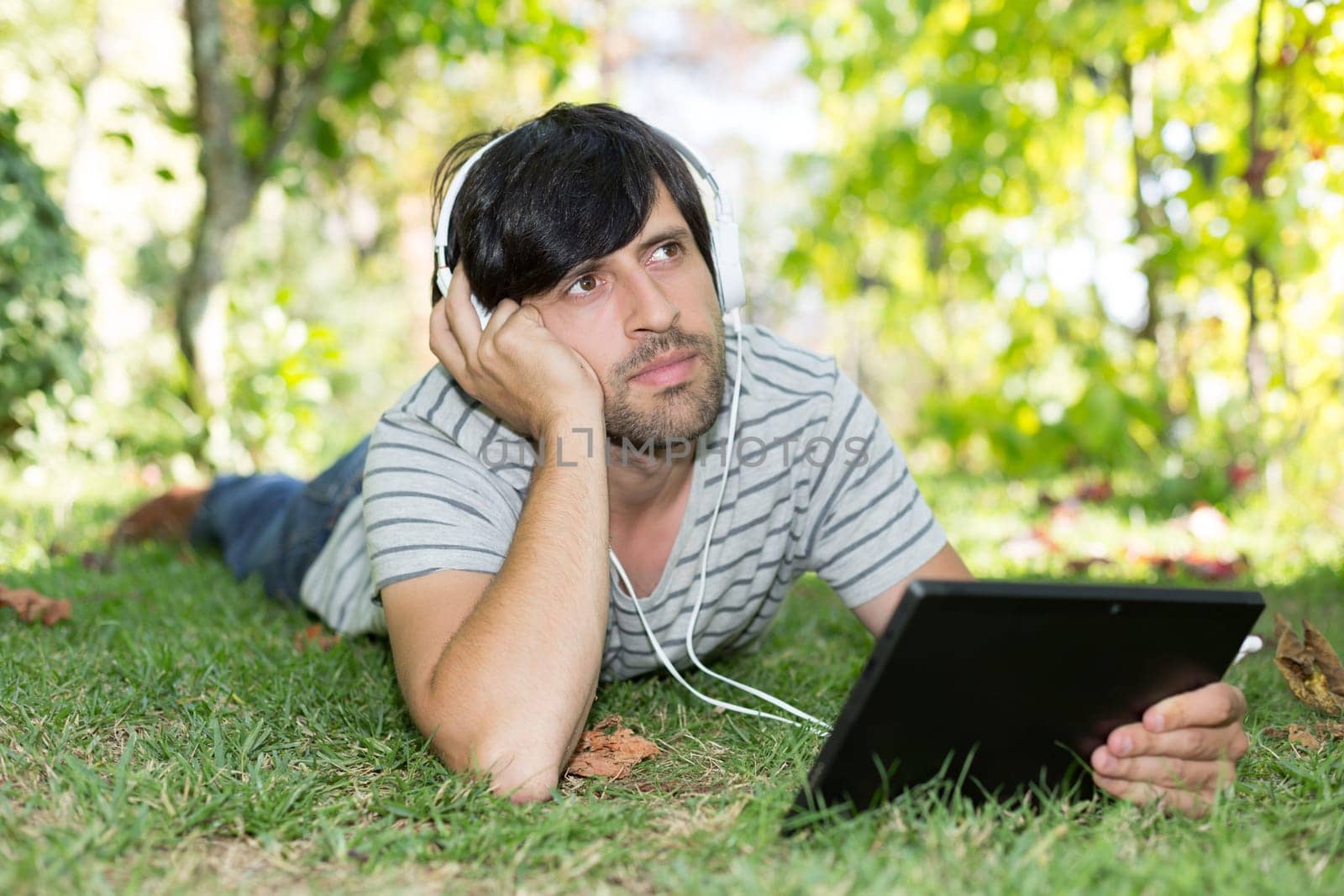 Young man relaxing with a touchscreen computer at a garden
