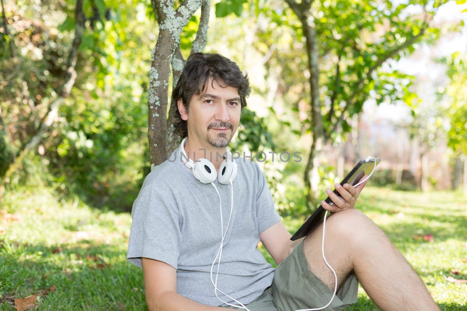 Young man relaxing with a tablet computer at a garden