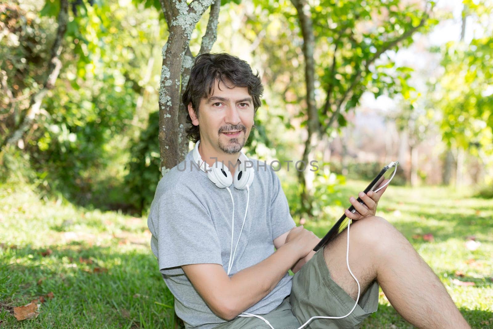 Young man relaxing with a tablet computer at a garden