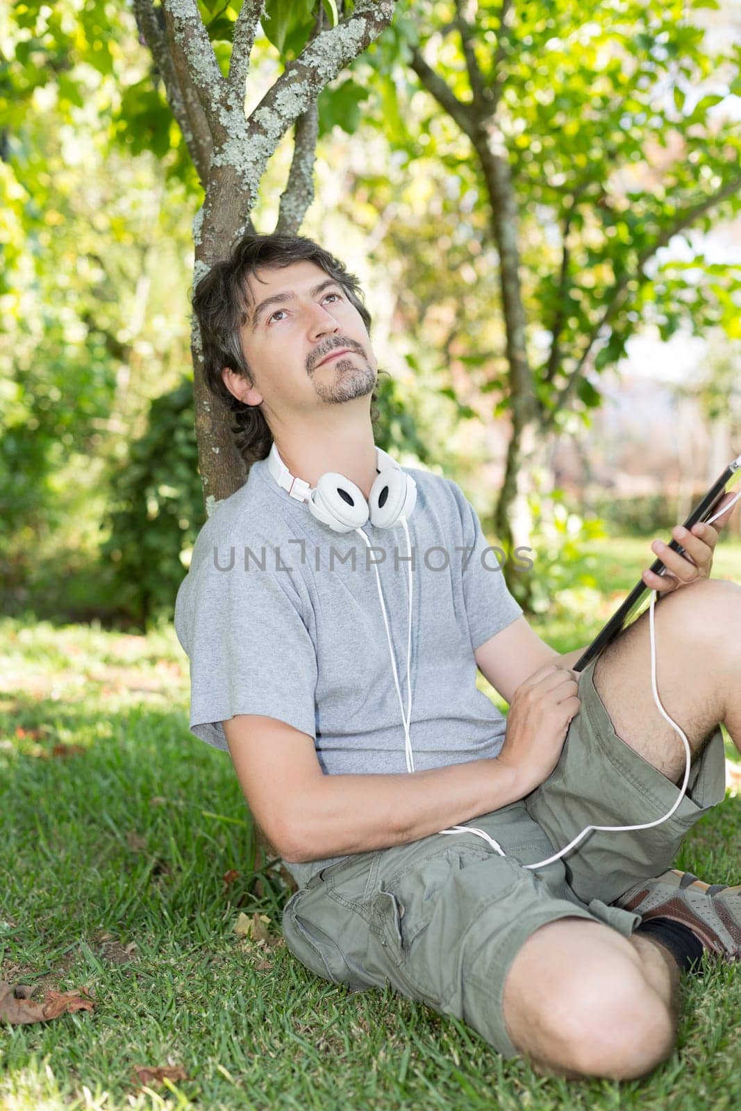 Young man relaxing with a tablet computer at a garden
