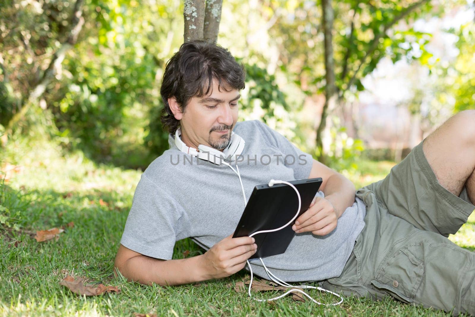 Young man relaxing with a tablet computer at a garden