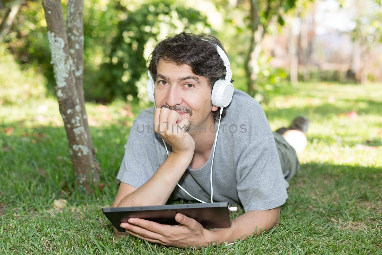 Young man relaxing with a touchscreen computer at a garden