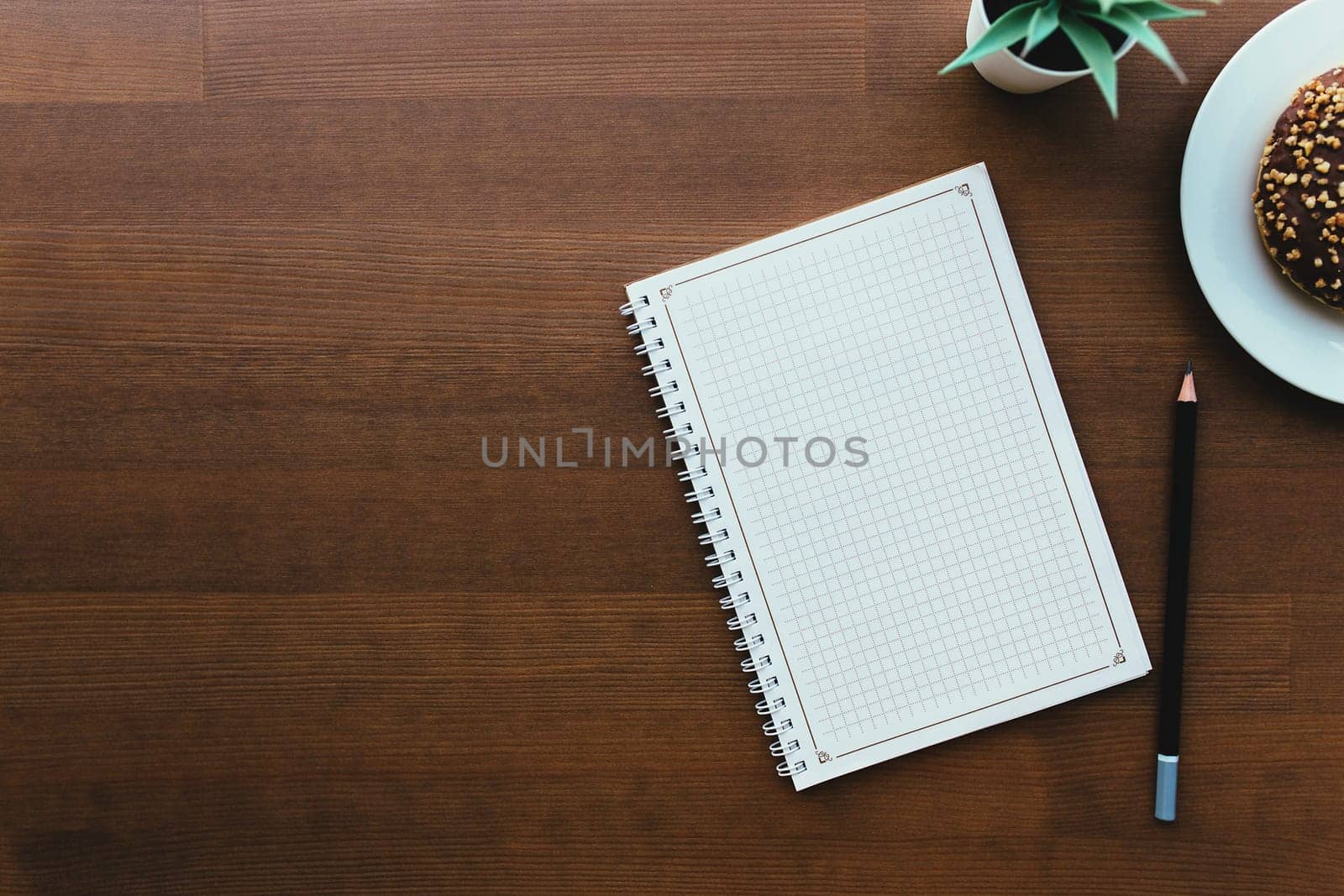 Donuts on the white plate and notebook on the wooden table. High quality photo
