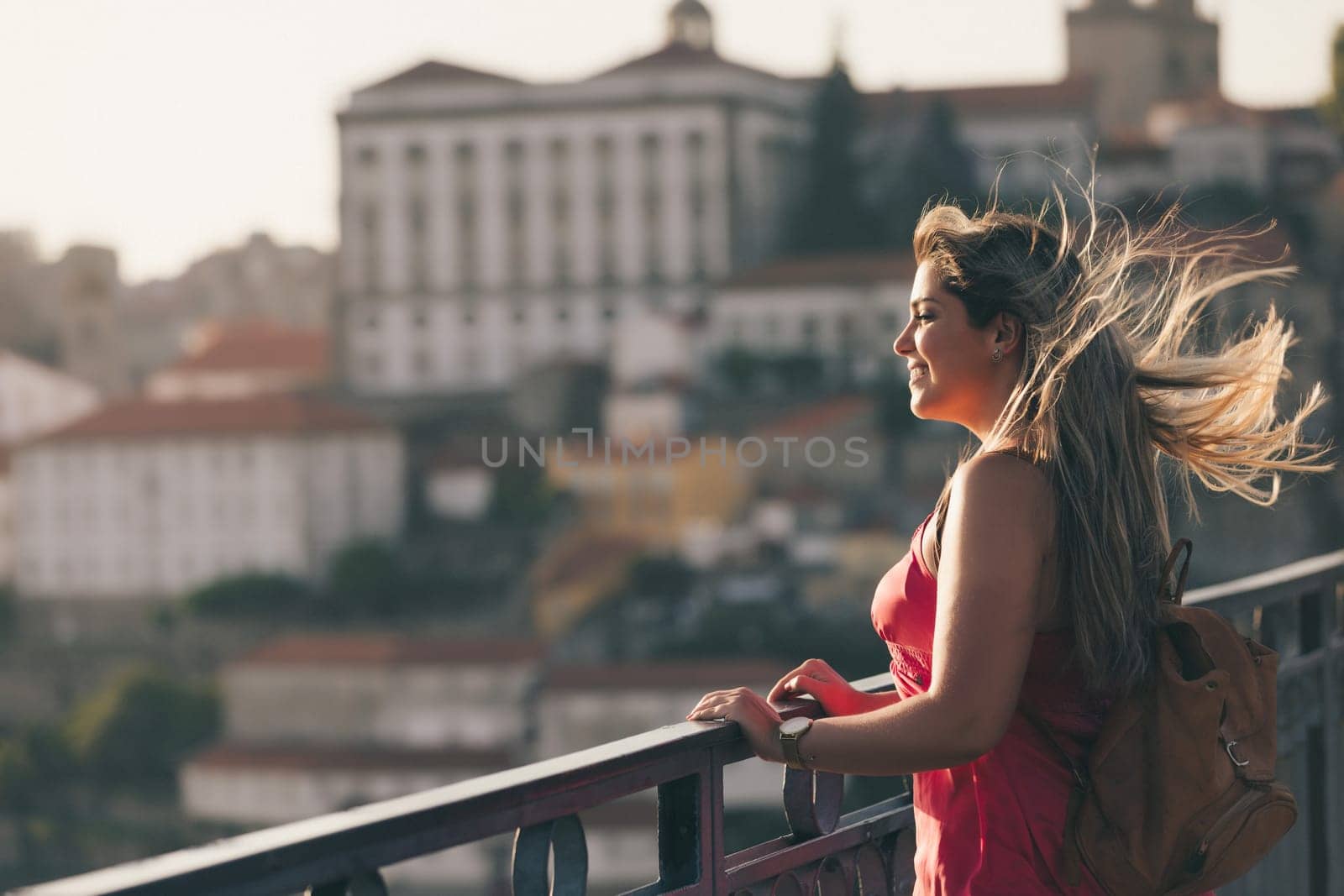 Young woman tourist enjoying beautiful landscape view on the old town with river and famous iron bridge during the sunset in Porto city, Portugal