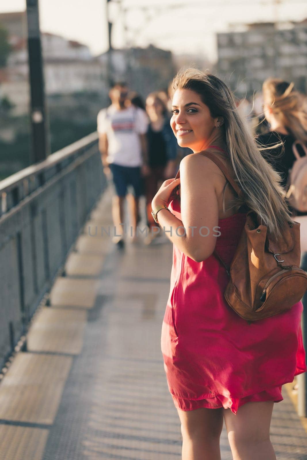 Young woman tourist enjoying beautiful landscape view on the old town with river and famous iron bridge during the sunset in Porto city, Portugal