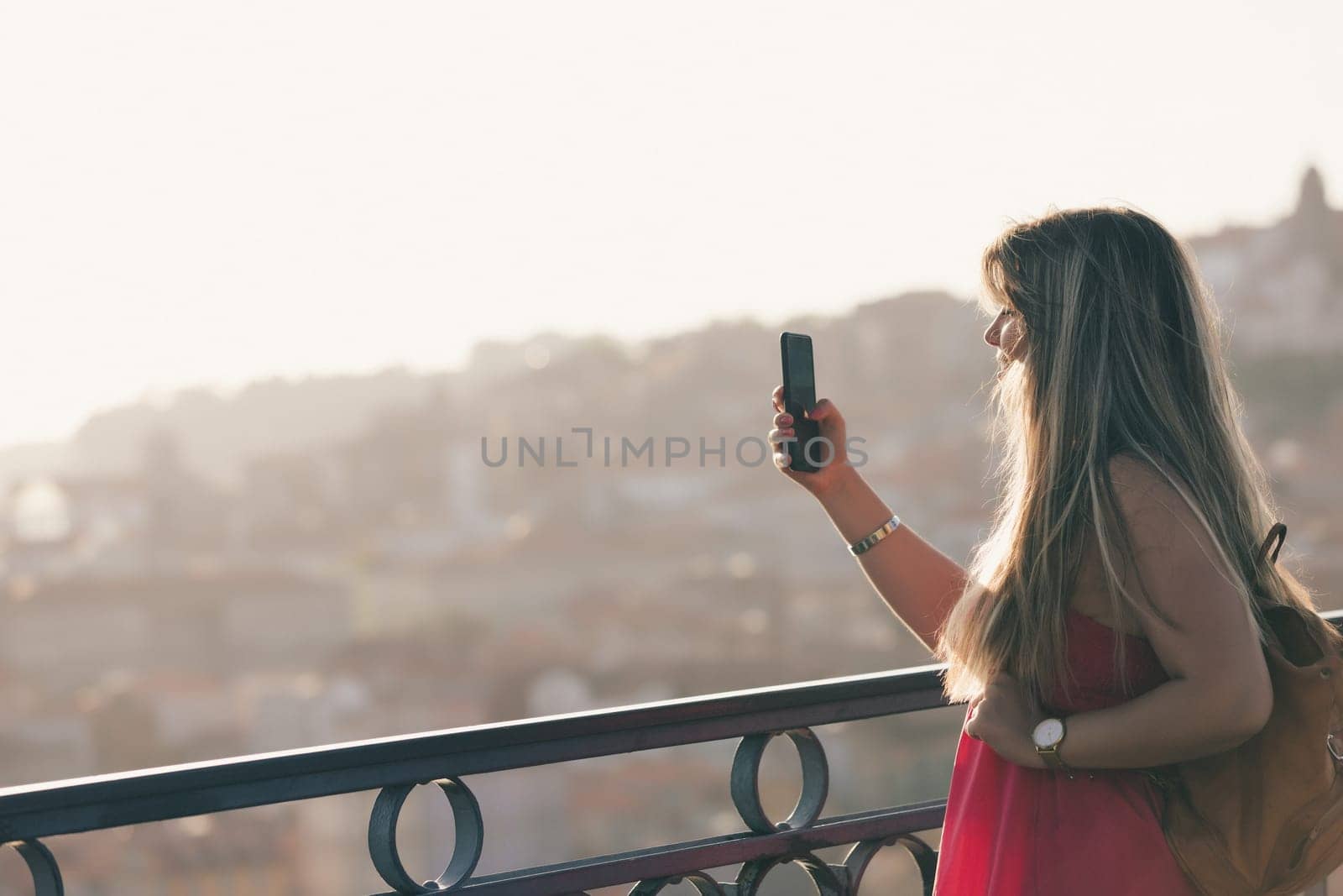Young woman tourist enjoying beautiful landscape view on the old town with river and famous iron bridge during the sunset in Porto city, Portugal