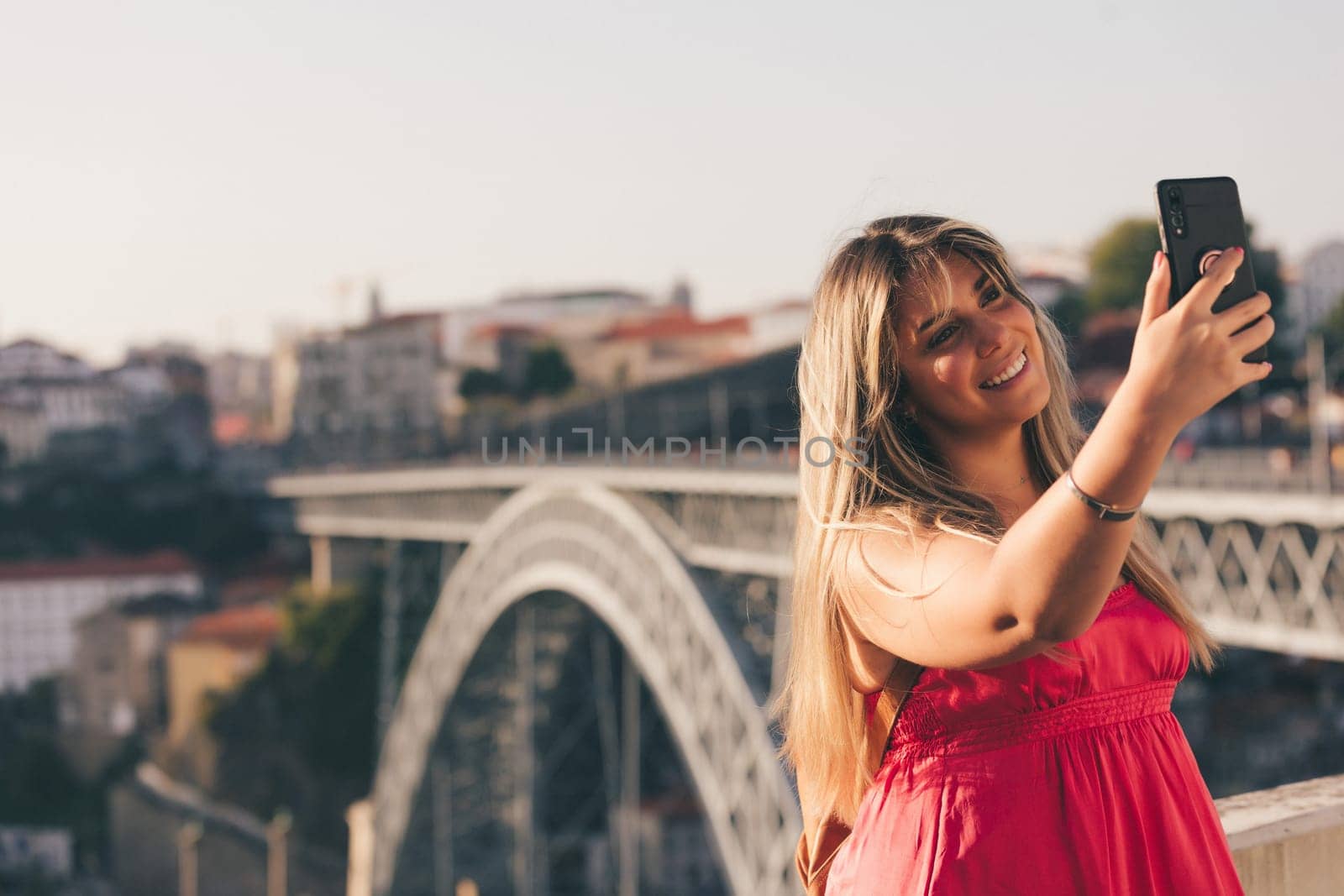 Young woman tourist enjoying beautiful landscape view on the old town with river and famous iron bridge during the sunset in Porto city, Portugal