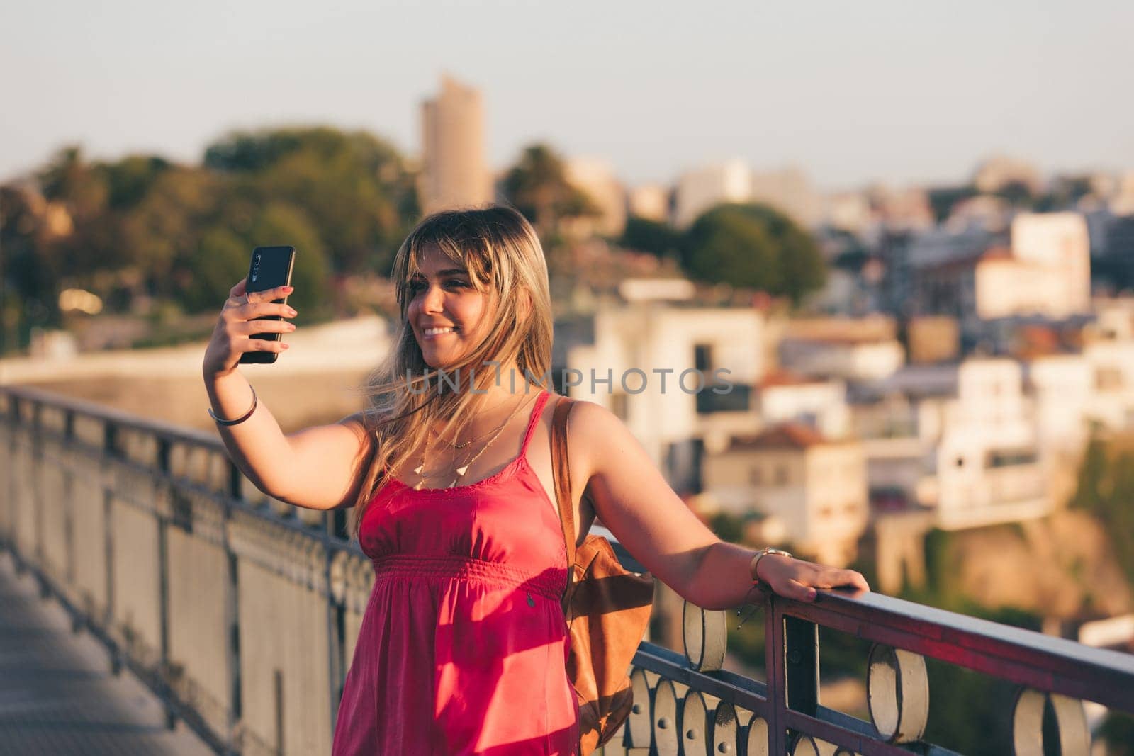 Young woman tourist enjoying beautiful landscape view on the old town with river and famous iron bridge during the sunset in Porto city, Portugal