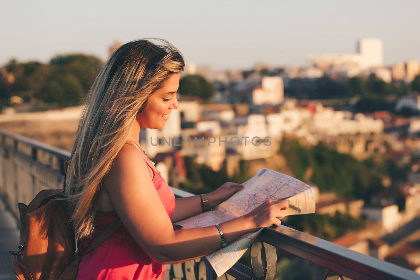 Young woman tourist enjoying beautiful landscape view on the old town with river and famous iron bridge during the sunset in Porto city, Portugal