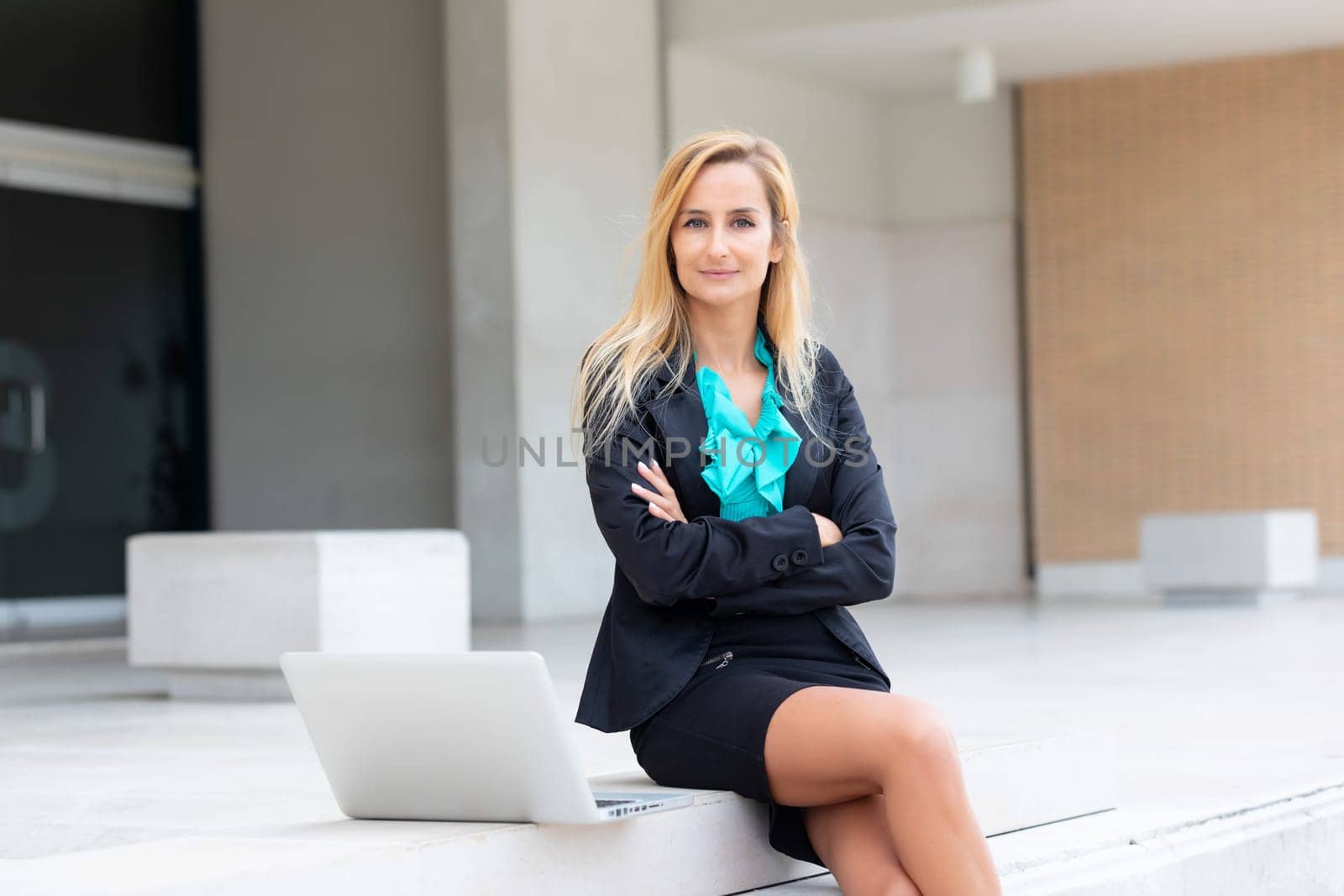 Young attractive businesswoman sitting on the stairs and using modern laptop