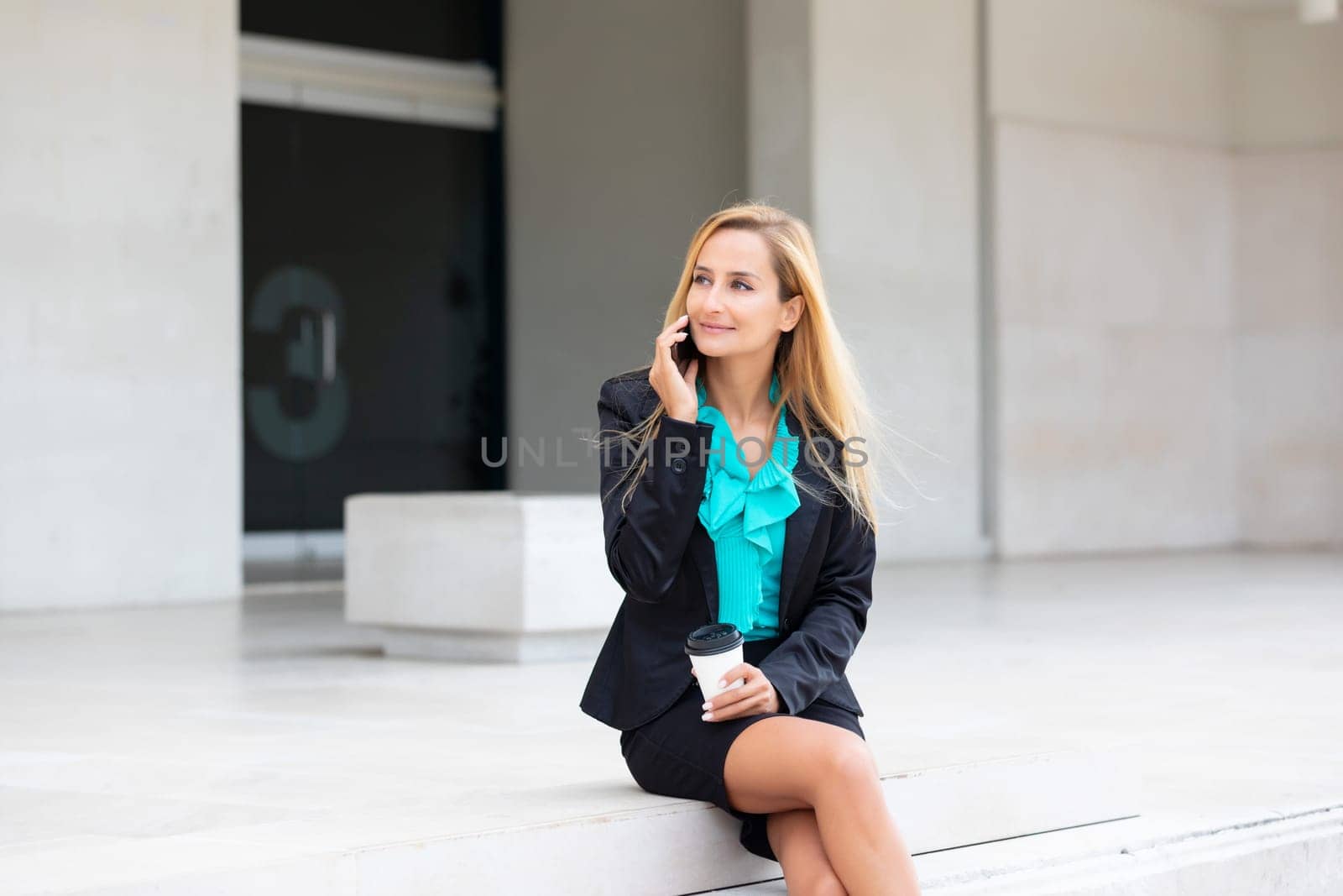 Business woman with coffe and talking on the phone near office