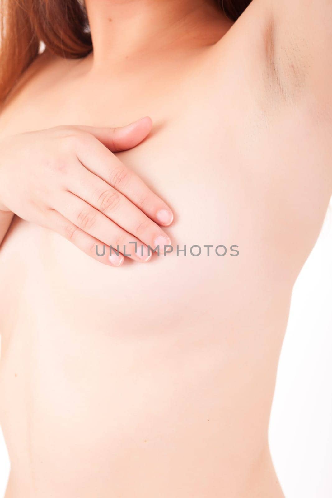 Young Caucasian adult woman examining her breast for lumps or signs of breast cancer