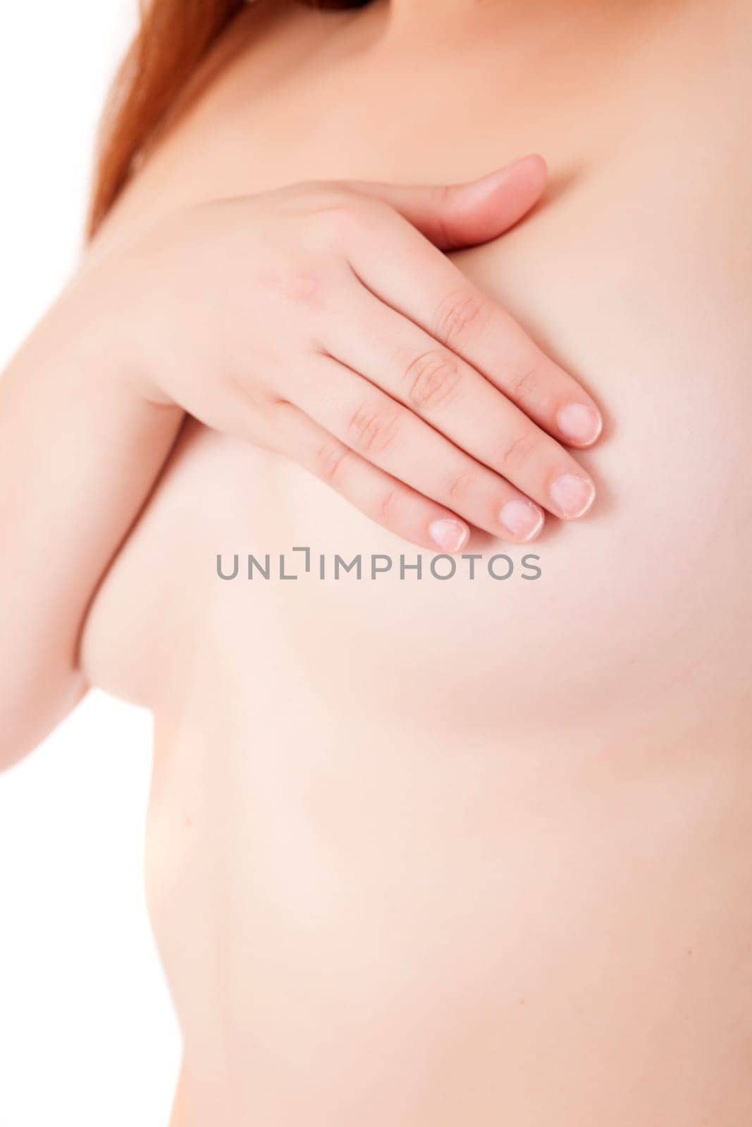 Young Caucasian adult woman examining her breast for lumps or signs of breast cancer