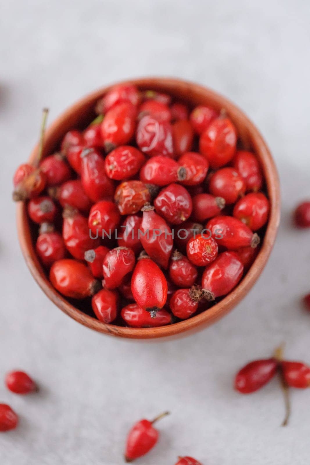 Medicinal plants and herbs. Rose hips berries on concrete background with copy space. Dried fruits for herbal teas and essential oils. Selective focus. Vertical orientation. Flat lay.